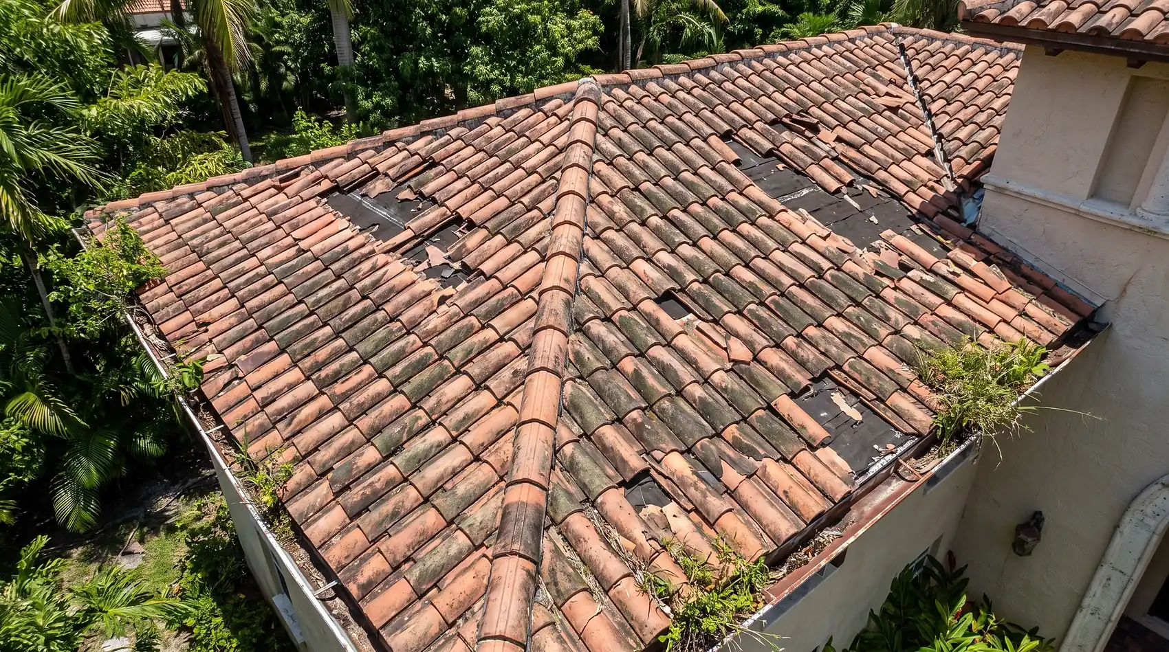 An aged failing tile roof with algae streaking and displaced tiles