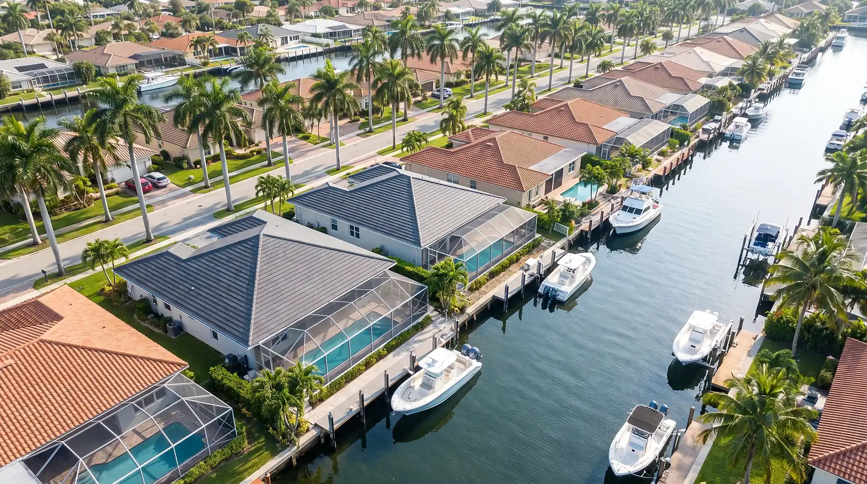 Low aerial over a Fort Lauderdale finger-canal street of tile roofs