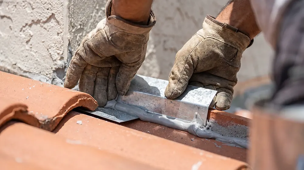 New step flashing sealed where a tile roof meets a stucco wall